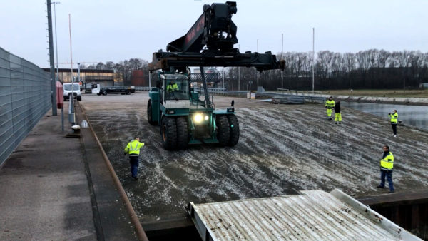 Ferrari-Reachstacker fährt über Rampe auf Binnenschiff