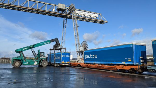 Umschlag von blauen Sattelaufliegern mittels Reachstacker auf Zug im bayernhafen Aschaffenburg