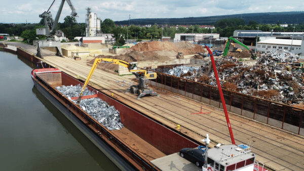 Mobilbagger verlädt Schrott in ein Binnenschiff